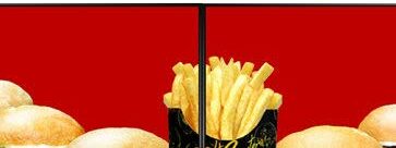 A portion of chips in a black container is centred against a vivid red background on digital signage, flanked by several round golden-brown burger buns on either side.