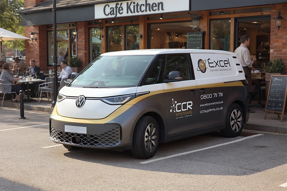 A branded Volkswagen van displaying Excel, CCR Systems, and EPOS logos is parked outside a café, while people dine at outdoor tables beside a brick building marked Café Kitchen.