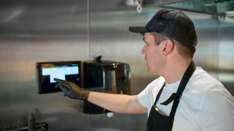 Restaurant Kitchen Staff Receiving Order Ticket with Digital Device Screen
