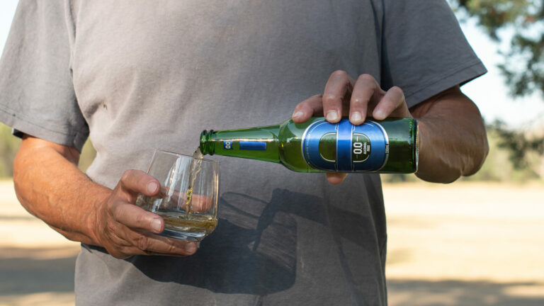 Man pouring a zero alcohol beer from a bottle into a glass
