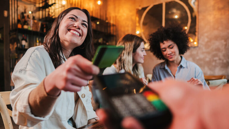 Lady smiling while tapping a card on a pyment machine at the bar