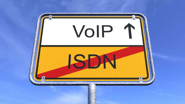 A road sign against a blue sky showing VoIP above an arrow and ISDN crossed out with a red diagonal line, symbolising a telecommunications upgrade.